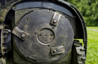 Beschädigte und stumpfe Mähroboter Messer mit Rasen im Hintergrund